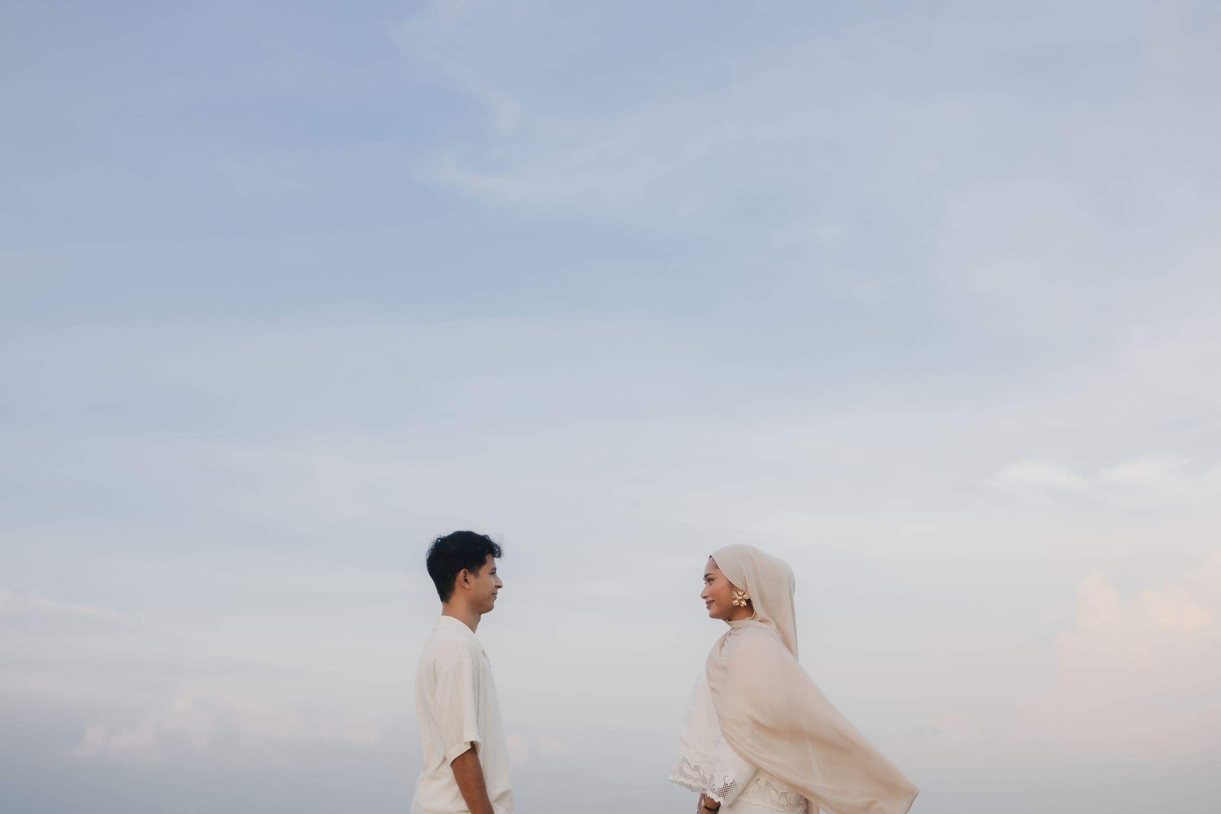 Amir and Yasmin facing each other against a soft evening sky